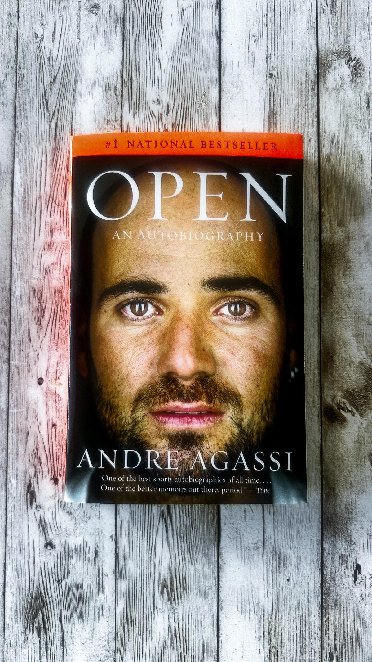 Open book by Andre Agassi on a wood board.