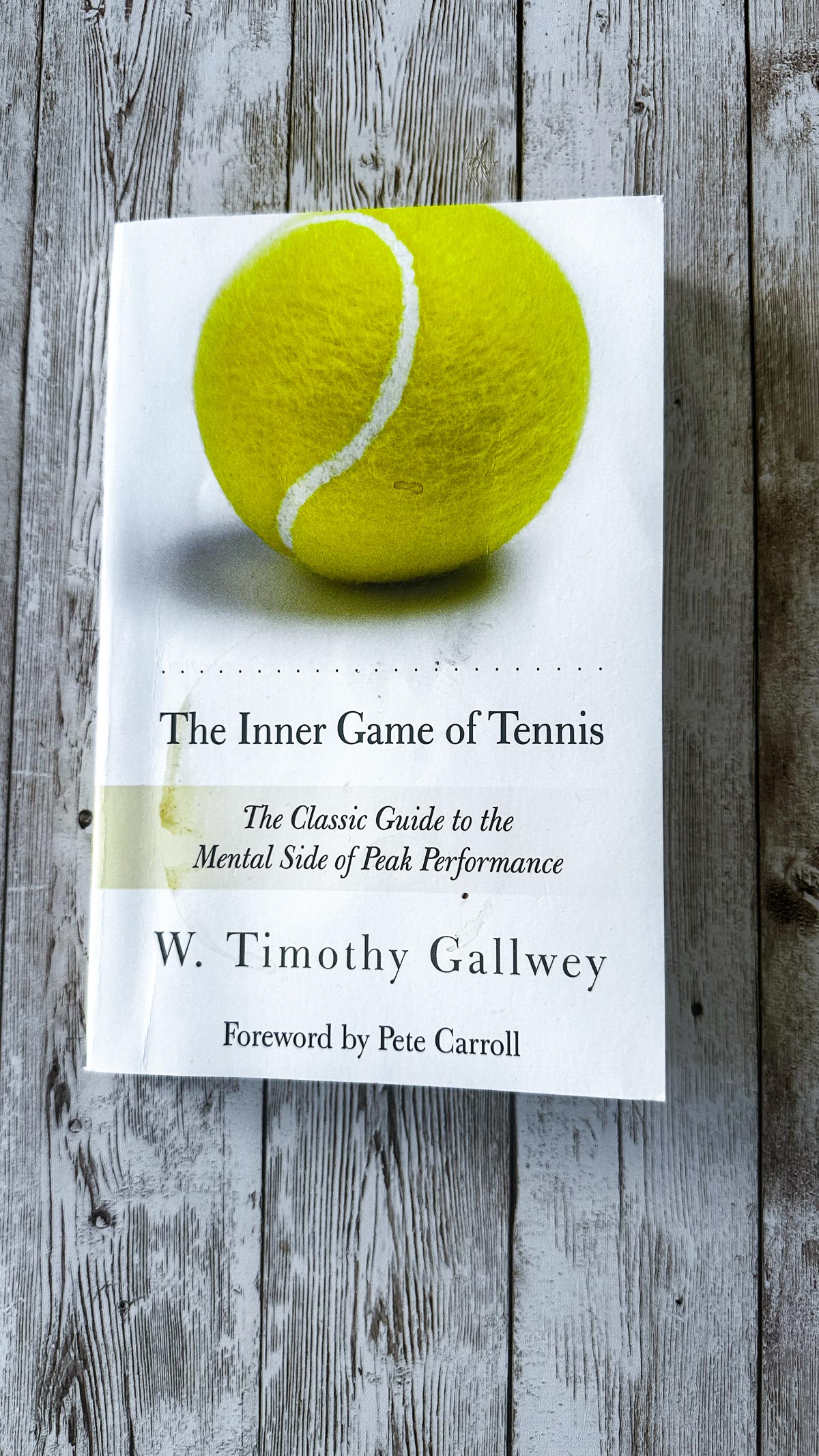 The Inner Game of Tennis book photographed on a wood board.