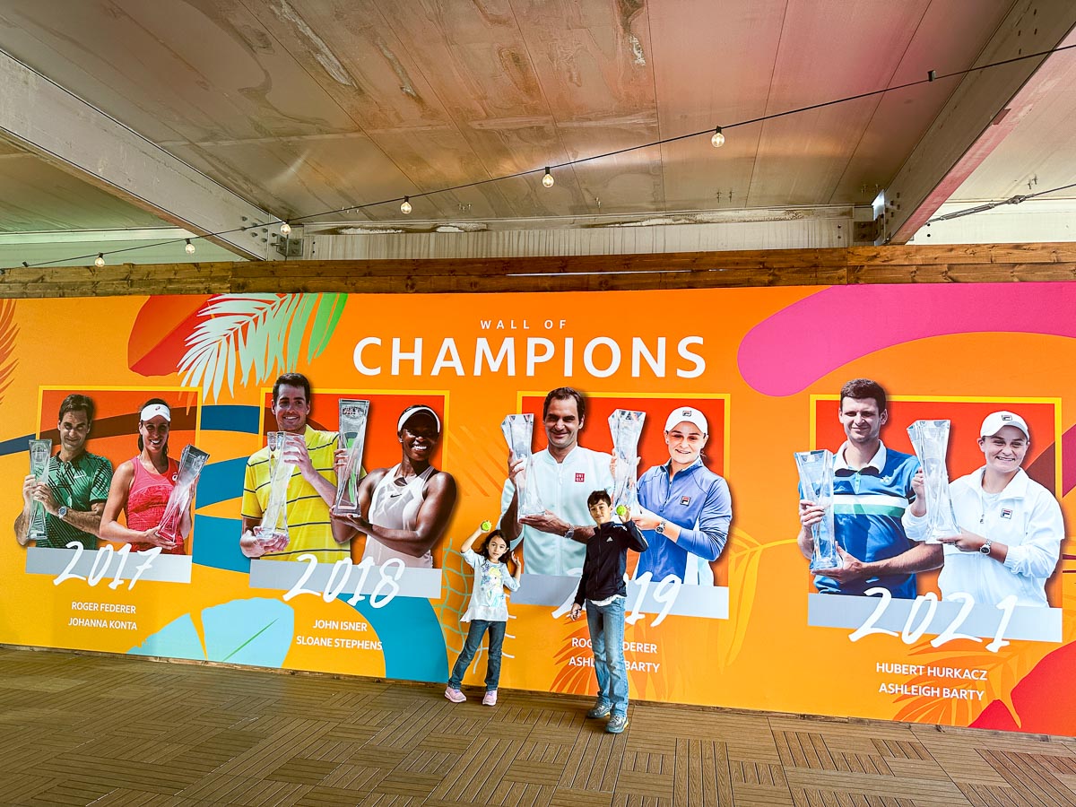 Our kids posing with a tennis ball in their hands at Wall of Champions at Miami Open 2023.